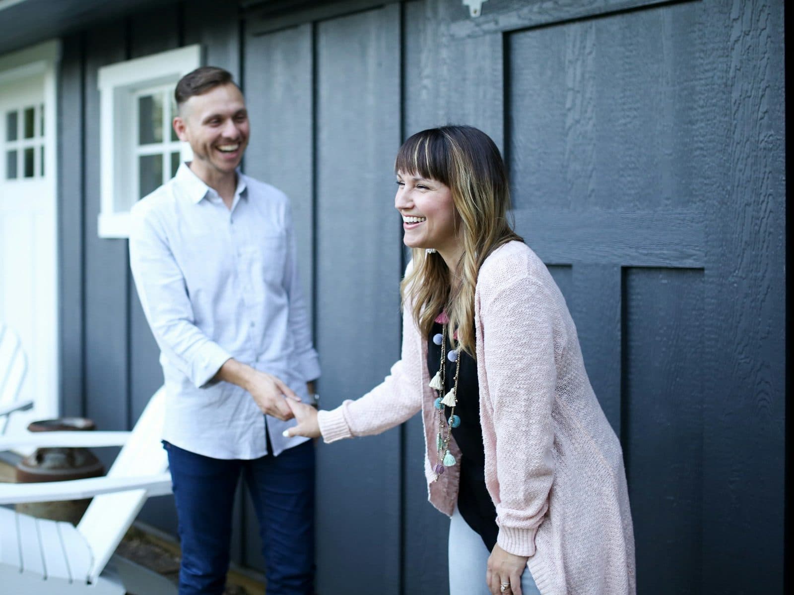 Couple souriant devant la porte de sa maison